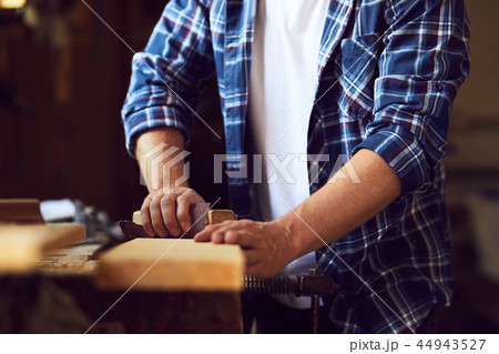 Carpenter works with sandpaper on a wooden plank Carpenter works with sandpaper on a wooden plank 44943527