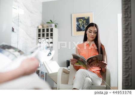 Calm woman is relaxing with magazine in salon Calm woman is relaxing with magazine in salon 44953376