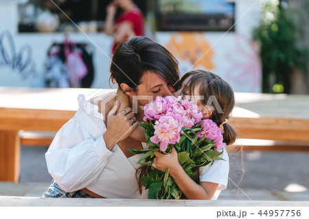 Mother and daughter kissing bouquets of peonies Mother and daughter kissing bouquets of peonies 44957756