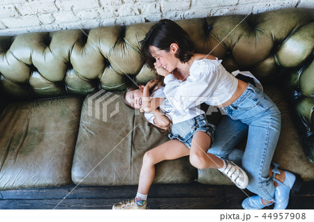 Mom and her little girl have fun on the couch Mom and her little girl have fun on the couch 44957908