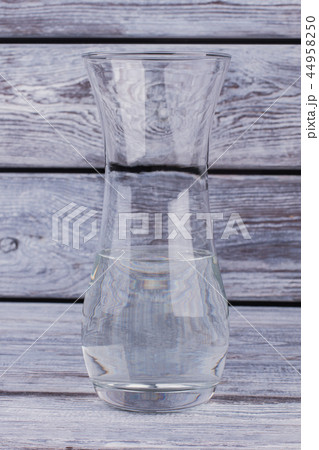 Clear glass vase with water on wooden background. Clear glass vase with water on wooden background. 44958250