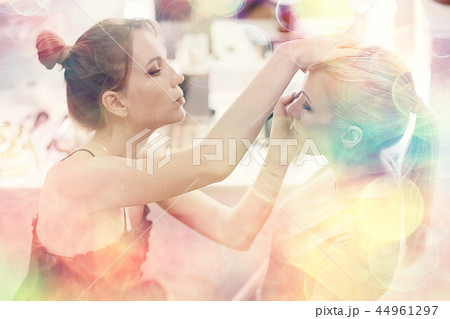 make-up salon on a blurred background with a pink bokeh / client makeup salon, a young girl with beautiful skin and a face doing make-up in the salon 44961297