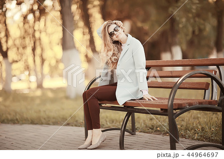adult girl sitting on a bench in the park / beautiful model woman resting on a bench, cheerful happy girl adult girl sitting on a bench in the park / beautiful model woman resting on a bench, cheerful happy girl 44964697