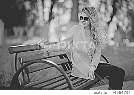 adult girl sitting on a bench in the park / beautiful model woman resting on a bench, cheerful happy girl 44964734