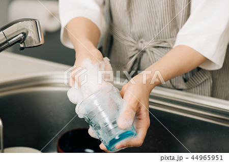 キッチンでコップを洗う若い主婦 日本人女性の写真素材
