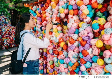 tourist hanging her wish dolls on the wish wall 44968056