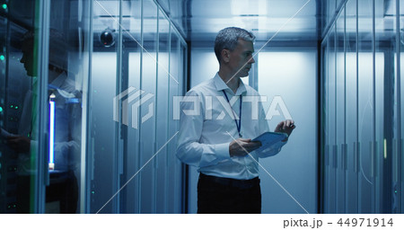 Technician works on a tablet in a data center Technician works on a tablet in a data center 44971914