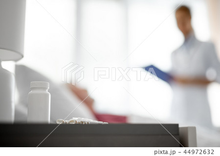 Medications lying on nightstand near patient bed 44972632