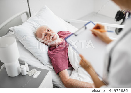 Smiling patient lying in bed near nightstand with medications 44972886
