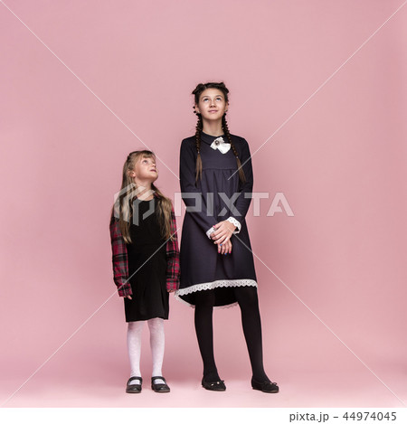 Cute stylish children on pink studio background. The beautiful teen girls standing together 44974045
