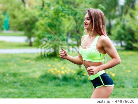 Beautiful young woman running in the green summer park. 44976020