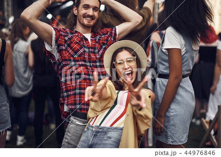 Cheerful girl showing victory gesture while friend standing behind her 44976846