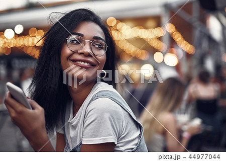 Charming girl with cellphone spending time outdoors Charming girl with cellphone spending time outdoors 44977044