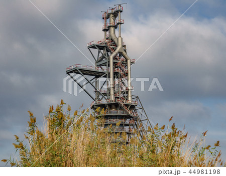 Old blast furnace behind bush and cloudy sky Old blast furnace behind bush and cloudy sky 44981198