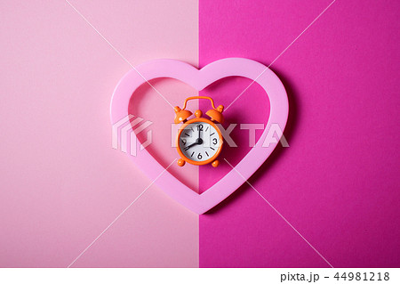 Orange alarm clock on a pink background. 44981218
