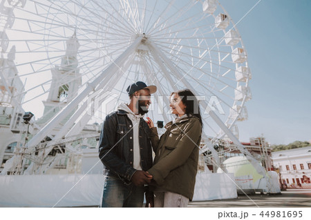 Cheerful young couple standing near Ferris wheel 44981695