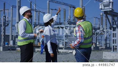 Three electrical workers reviewing documents on a tablet Three electrical workers reviewing documents on a tablet 44981747