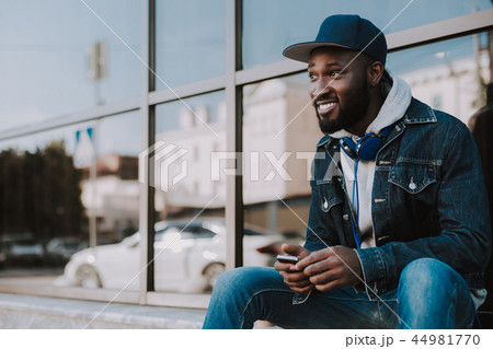 Cheerful afro american man using his mobile phone Cheerful afro american man using his mobile phone 44981770