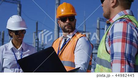 Three electrical workers reviewing documents outside Three electrical workers reviewing documents outside 44982445
