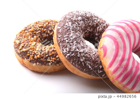Assorted doughnuts in the glaze, colorful sprinkles and nuts on a white background. Assorted doughnuts in the glaze, colorful sprinkles and nuts on a white background. 44982656