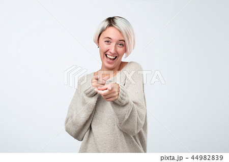 Beautiful young woman points with finger and scoffs, short haircut, studio photo Beautiful young woman points with finger and scoffs, short haircut, studio photo 44982839