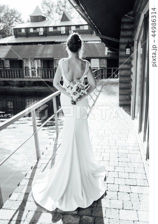 View of unrecognazible young woman in wedding dress standing by back and looking away. View of unrecognazible young woman in wedding dress standing by back and looking away. 44986314