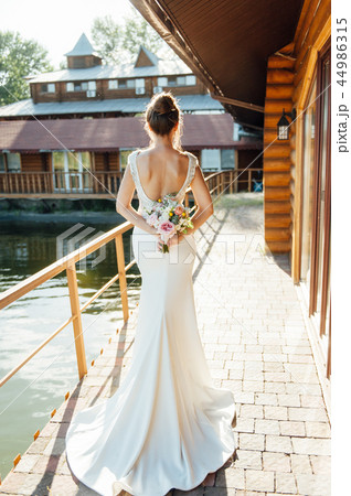 View of unrecognazible young woman in wedding dress standing by back and looking away. 44986315