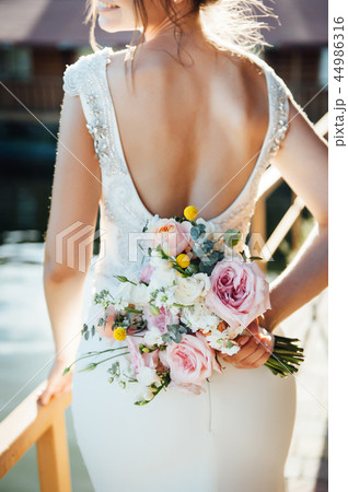 View of unrecognazible young woman in wedding dress standing by back and looking away. 44986316