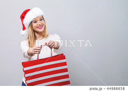 Young woman with santa hat holding a shopping bag Young woman with santa hat holding a shopping bag 44986658