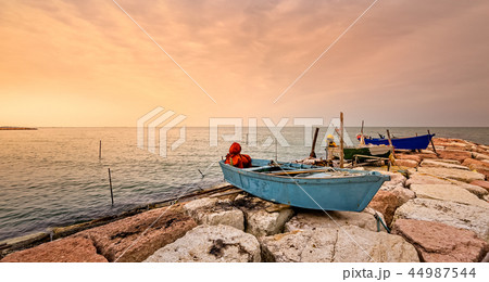 Fishing boat moored on cliff at sunset. 44987544