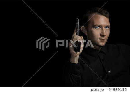 young man close up portrait, on black with pistol young man close up portrait, on black with pistol 44989156