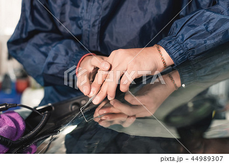 Close up Car glaze worker fixing and repairing a windshield or windshield of a car at a garage Close up Car glaze worker fixing and repairing a windshield or windshield of a car at a garage 44989307