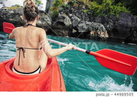 Woman paddles kayak in the lake with turquoise water. 44989505