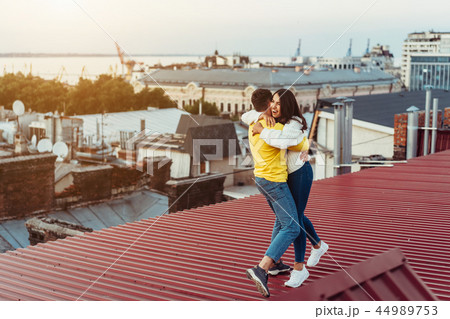 Loving young couple is standing on the roof of the house. Loving young couple is standing on the roof of the house. 44989753