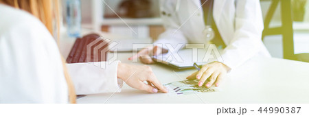 A beautiful young girl in a white robe is sitting at the desk in the office and communicating with A beautiful young girl in a white robe is sitting at the desk in the office and communicating with 44990387