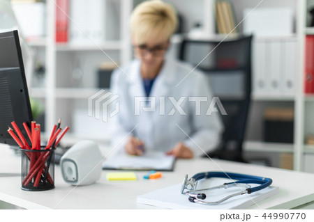 Photo with depth of field, highlighted focus on the phonendoscope. A young girl in a white robe Photo with depth of field, highlighted focus on the phonendoscope. A young girl in a white robe 44990770