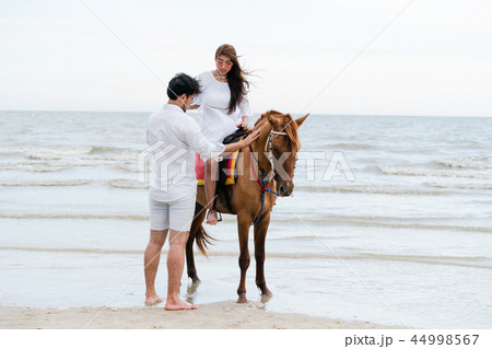 Young couple goes horse riding on tropical beach. 44998567