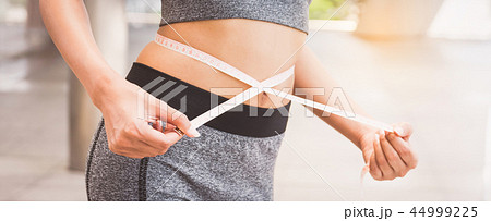 woman measuring her waist with a tape measure 44999225