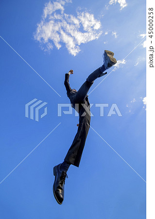 青空をバックにジャンプするスーツ姿の若いビジネスマン1人。元気・パワー・成功・挑戦イメージ 45000258