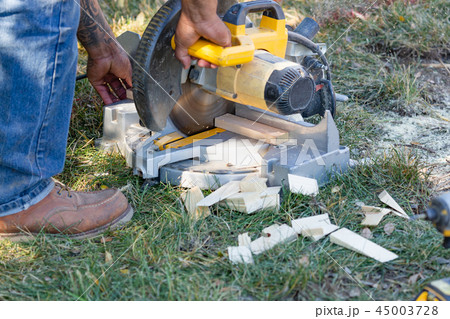 Worker Using Electric Miter Saw At a Job Site Worker Using Electric Miter Saw At a Job Site 45003728