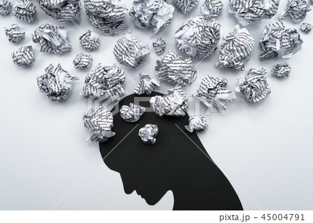 メンタルヘルスのイメージ。紙くずとうつむいた人のシルエット。 メンタルヘルスのイメージ。紙くずとうつむいた人のシルエット。 45004791