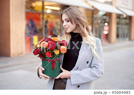 Caucasian fashion woman standing on the street near storefront shop windows holding flower-box with Caucasian fashion woman standing on the street near storefront shop windows holding flower-box with 45004985