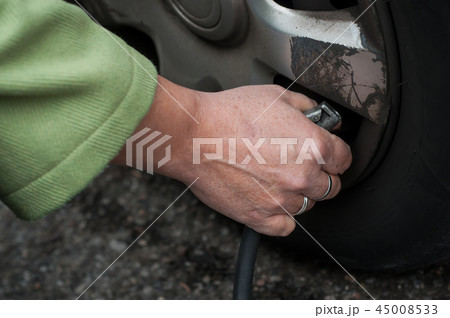 woman putting air into the tire from tire valve woman putting air into the tire from tire valve 45008533