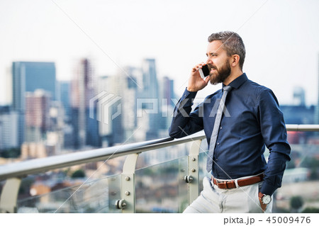 A portrait of businessman with smartphone standing against London view panorama. 45009476