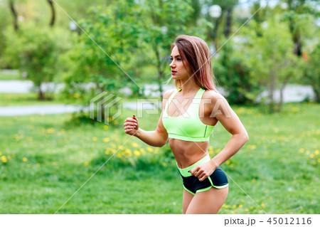Beautiful young woman running in the green summer park. 45012116