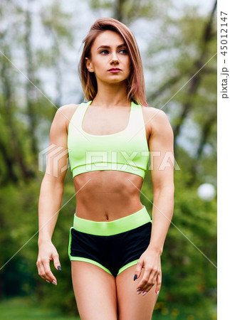 Sporty woman with perfect athletic body posing on sportsground. 45012147