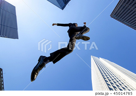 ビル街を青空バックにジャンプするスーツ姿のビジネスマン1人。挑戦,努力,成功,元気イメージ 45014765