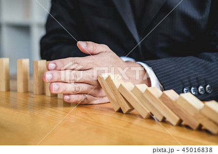 Wooden game strategy, Businessman hand stopping falling wooden d Wooden game strategy, Businessman hand stopping falling wooden d 45016838