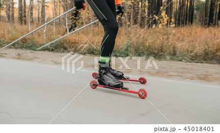 Training an athlete on the roller skaters. Biathlon ride on the roller skis with ski poles, in the Training an athlete on the roller skaters. Biathlon ride on the roller skis with ski poles, in the 45018401
