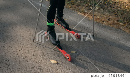 Training an athlete on the roller skaters. Biathlon ride on the roller skis with ski poles, in the 45018444
